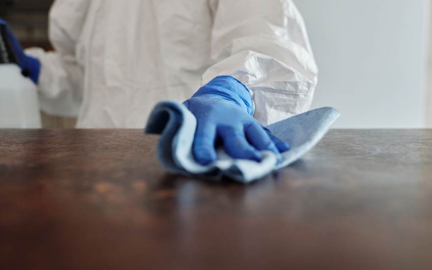 Web design for cleaning companies, shown with a gloved hand wiping a table
